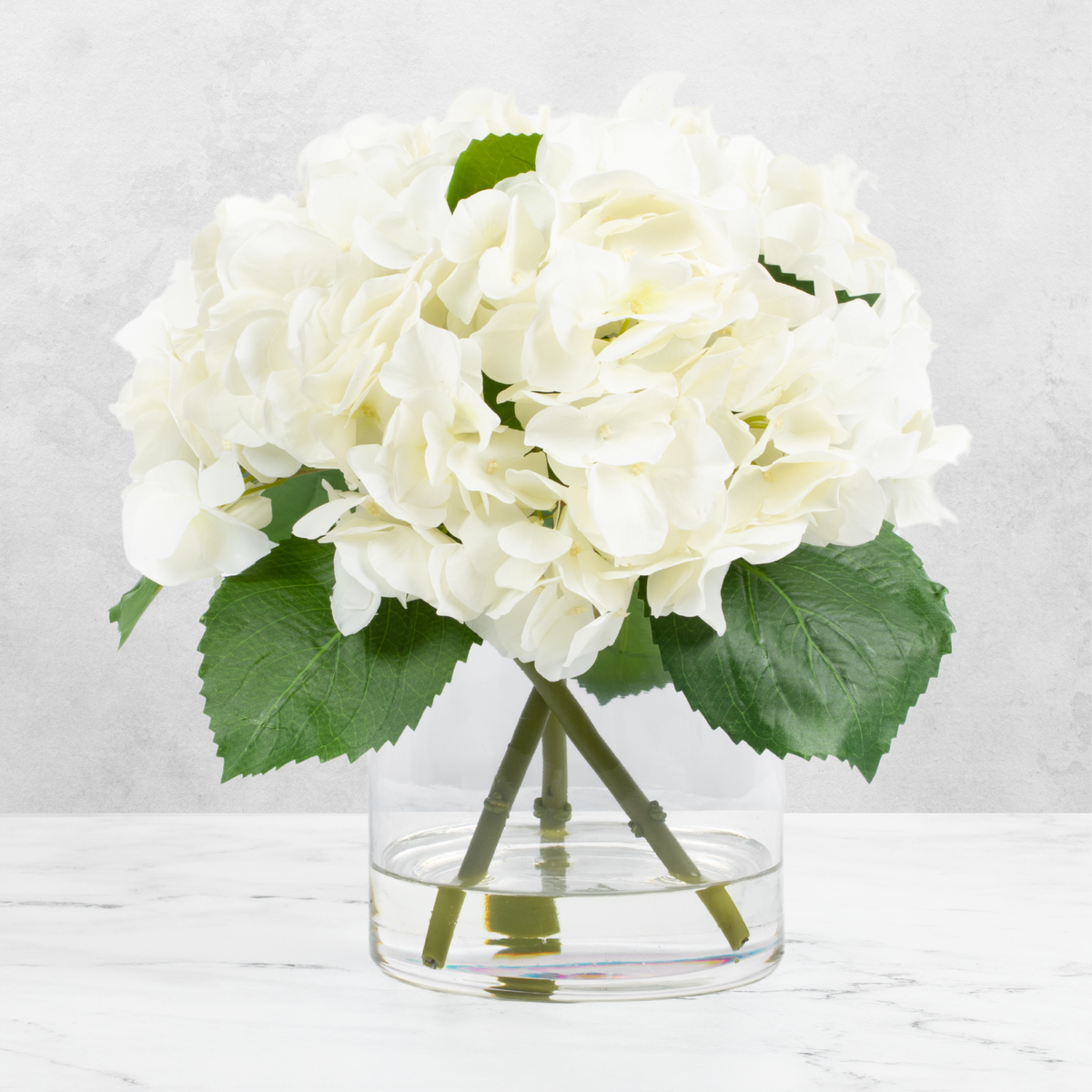 Faux hydrangea centerpiece arrangement in glass vase